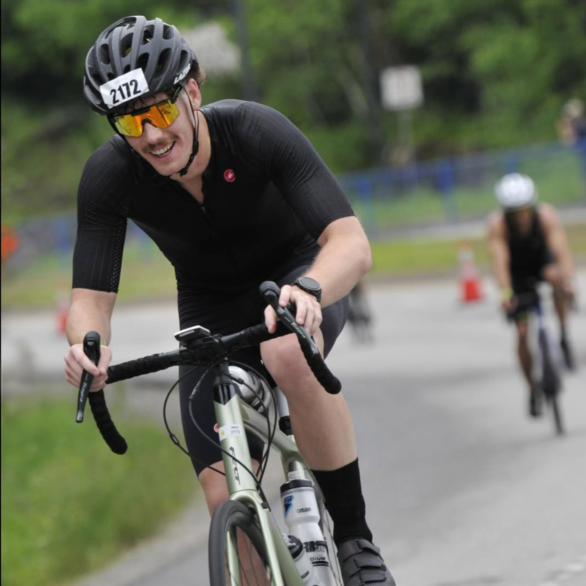Cyclist in a black outfit with helmet and sunglasses competing in a road race, symbolizing endurance, speed, and active lifestyle – Ero Evergreen supplement lifestyle imagery.