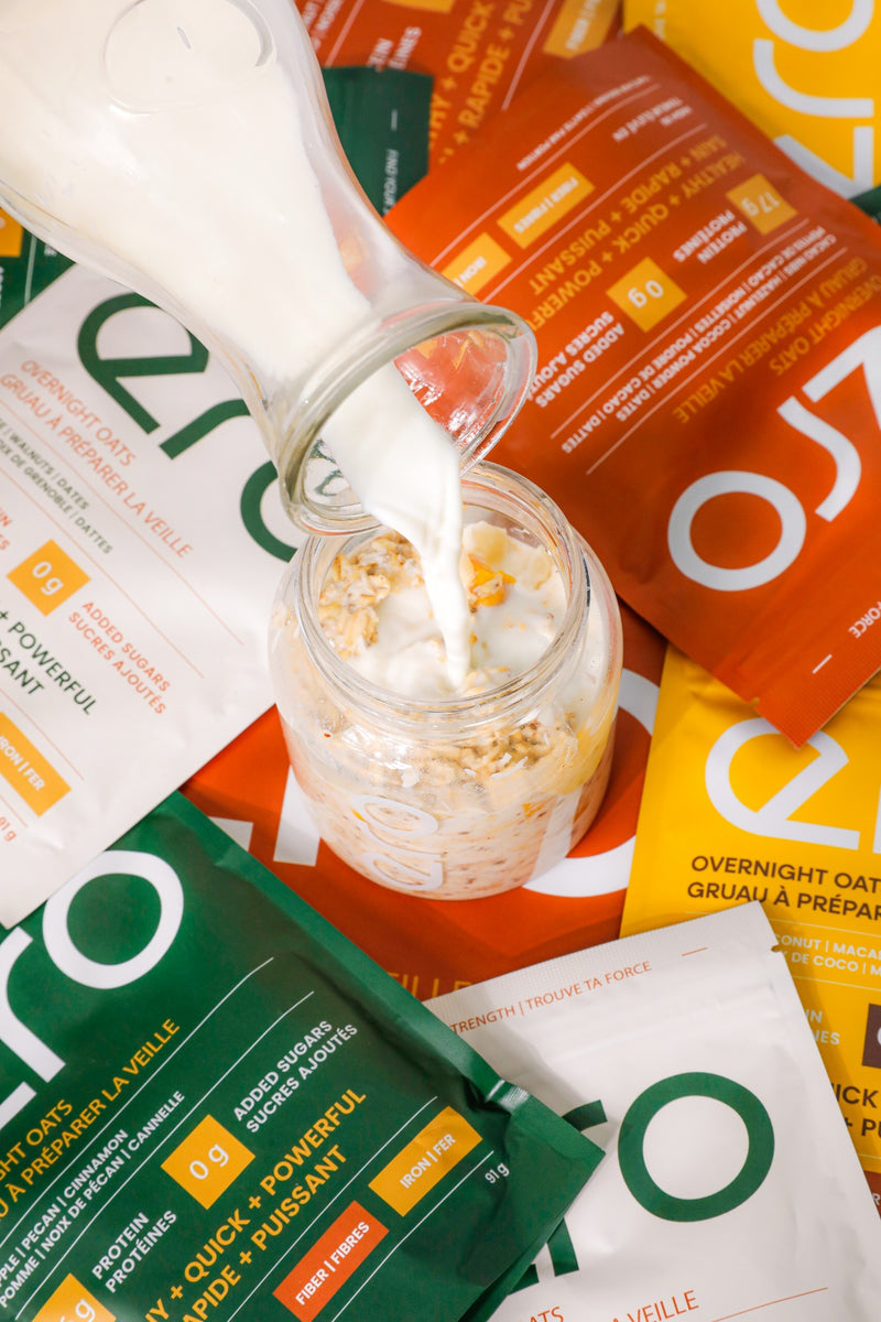 Milk being poured into a jar of ero overnight oats surrounded by flavour pouches