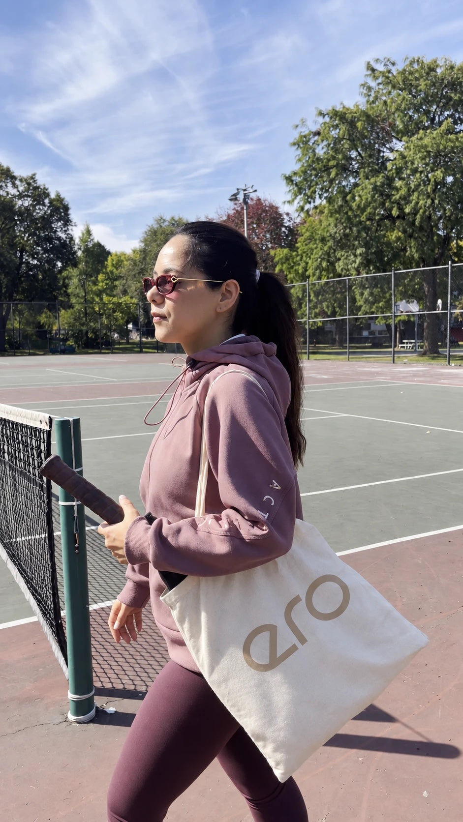 Woman carrying the ero cotton tote bag on her shoulder on an outdoor court