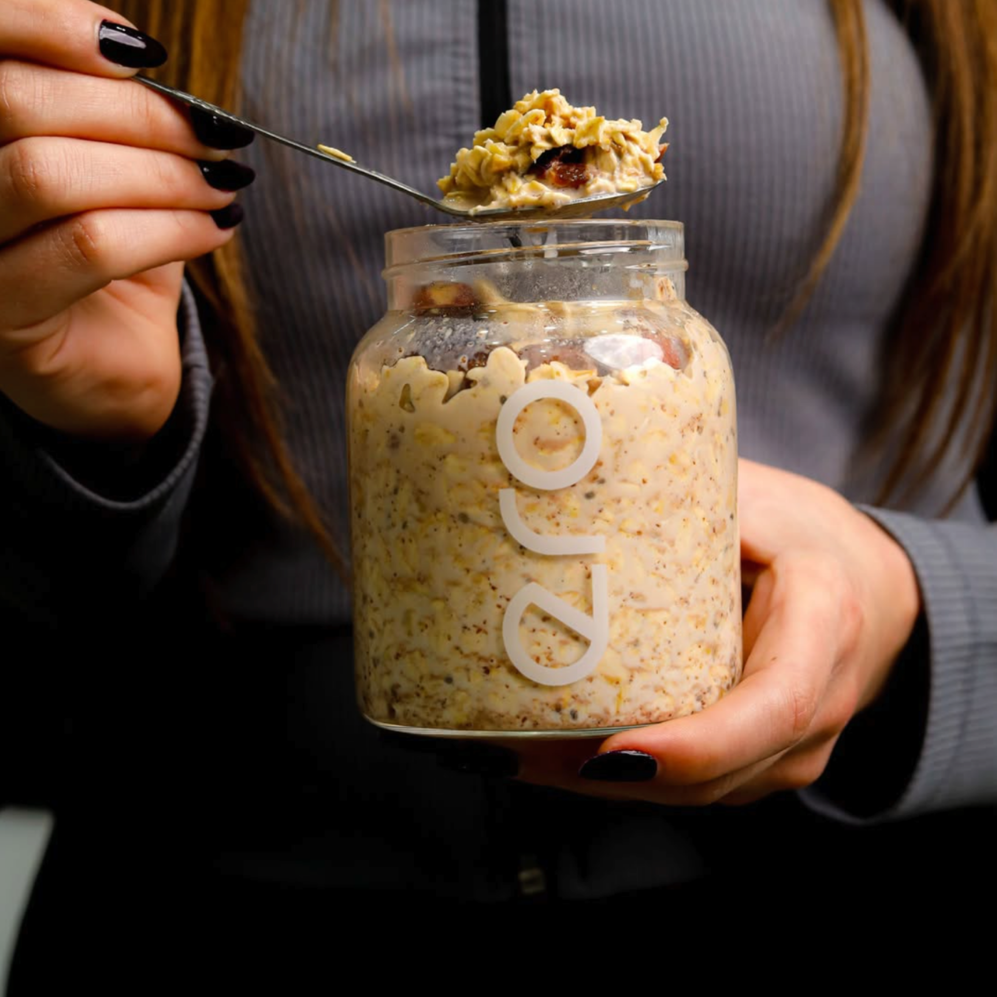 Glass jar of ero high-protein overnight oats with visible seeds, nuts, and fruit, ready to eat.